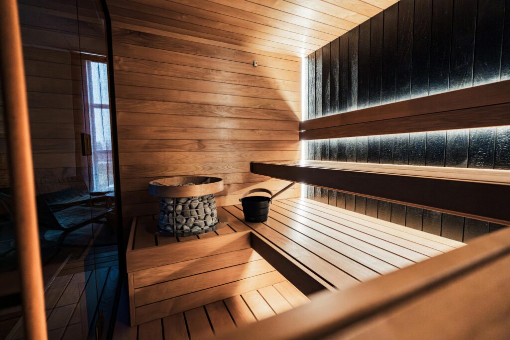 Elegant indoor sauna featuring wooden panels, sauna heater, and a tranquil ambiance.